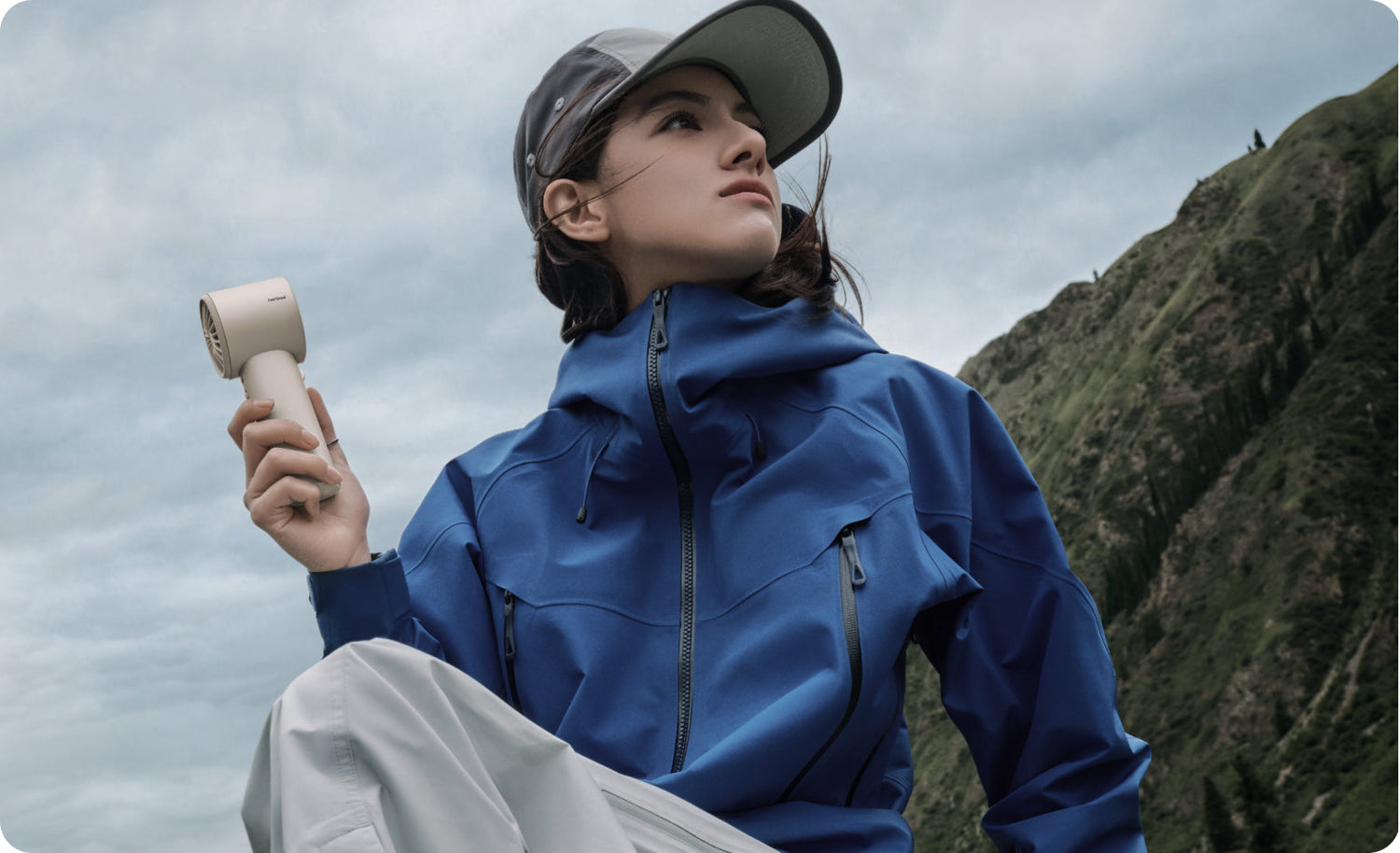 Woman holding a handheld fan while hiking in the mountains