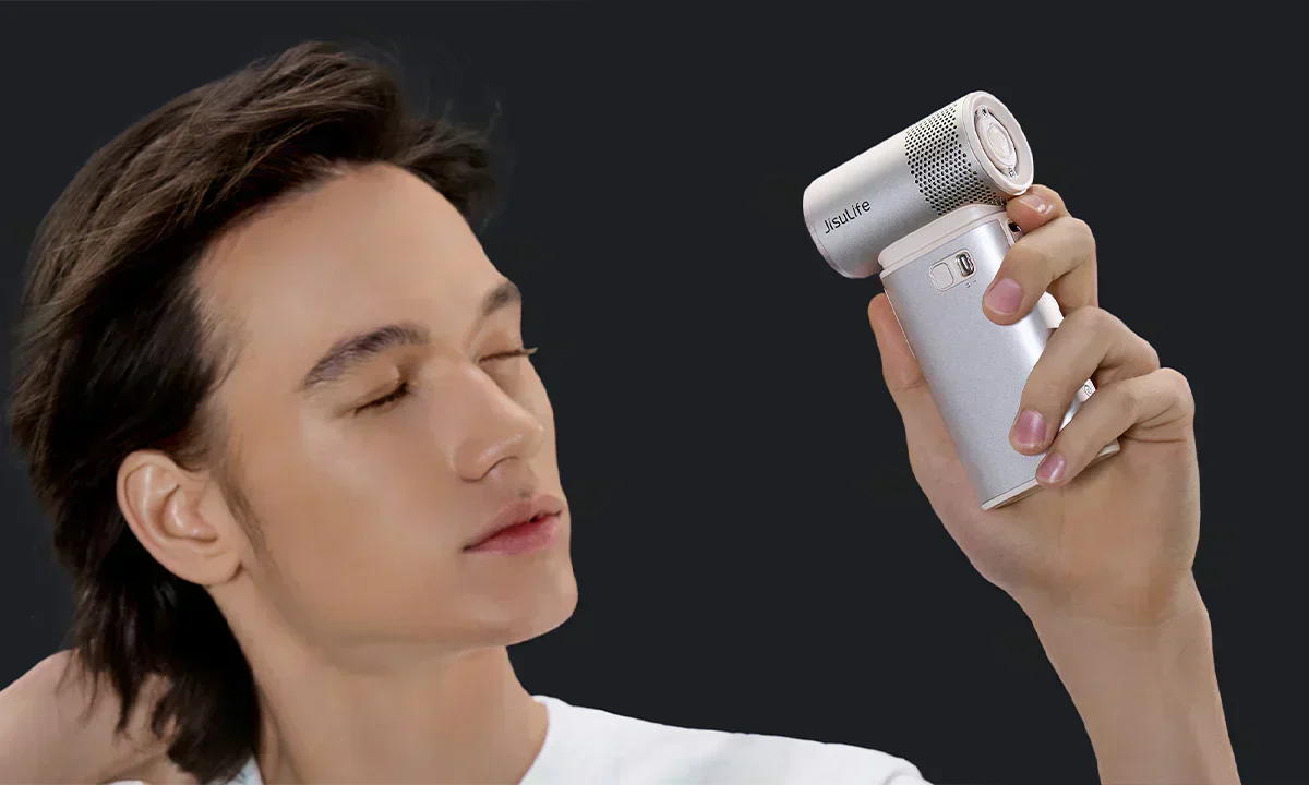 JISULIFE handheld fan held close to a man’s face as she enjoys a cooling breeze, eyes closed in a relaxed expression.