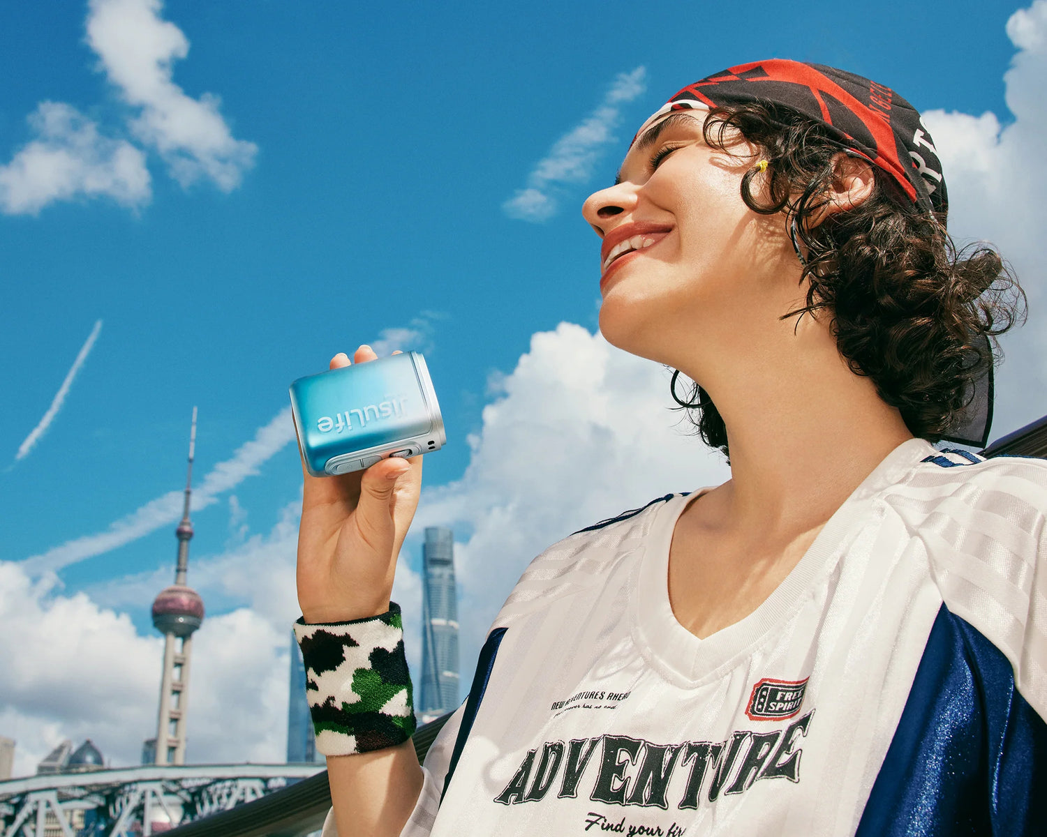 Woman uses a compact bladeless fan under a bright blue city sky