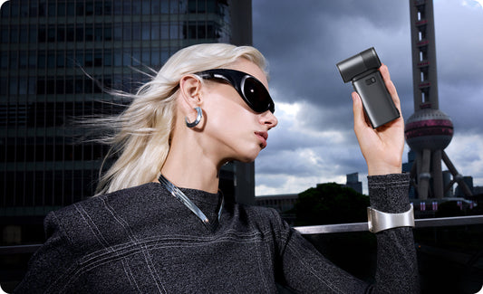 Stylish woman holding a JisuLife Pro series handheld fan to stay cool in a modern urban environment.