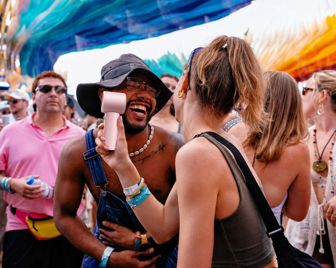 Woman holds a personal cooling fan in a crowded outdoor music festival