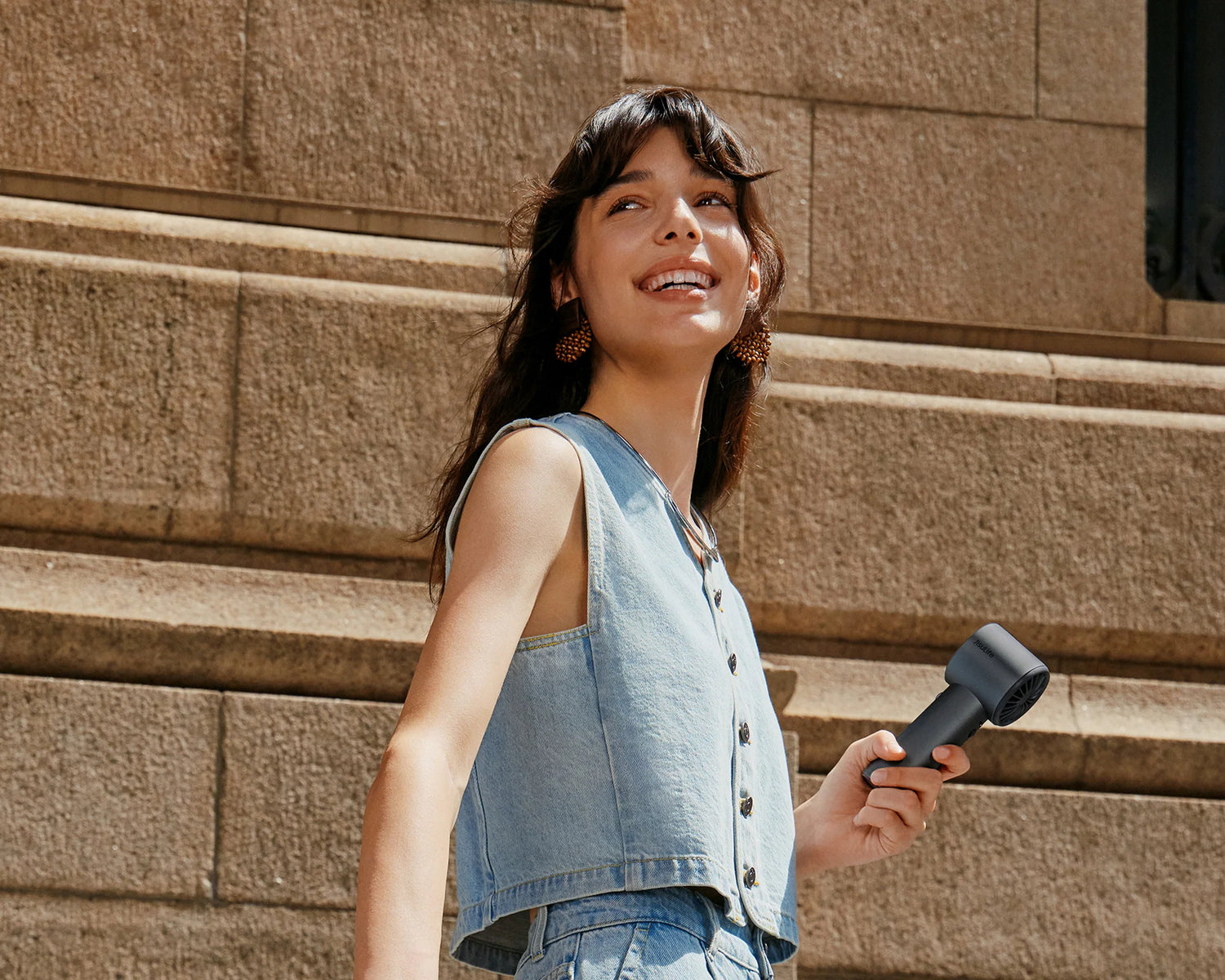 Woman carries a USB-C rechargeable fan while walking on a sunny city street