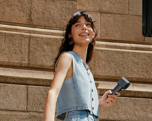 Woman carries a USB-C rechargeable fan while walking on a sunny city street